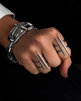 Hand wearing multiple silver bracelets and rings on a black background