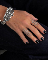 Hand wearing a silver bracelet and multiple rings with black nail polish on a dark background