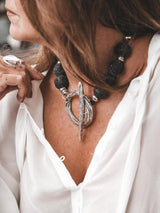 Chunky black lava stone beads on an 18-inch choker, featuring an oversized silver T-clasp, worn with a white blouse.