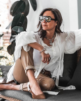 Textured heart charm bracelet in antique-plated silver, worn layered with a chunky chain and styled with a white blouse.