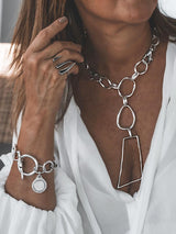Asymmetrical silver plated necklace with large irregular loops, chunky carabiner clasp, styled with a white blouse.