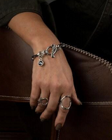 Silver oval link chain cuff bracelet featuring a Swarovski crystal charm and T-bar closure, worn with rings.