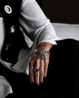 Chunky Cuban link chain bracelet featuring an engraved coin and sculpted pendant, worn on a wrist with a statement ring.