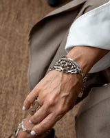 Close-up of a hand wearing multiple silver bracelets on a neutral background