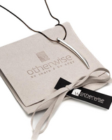 Layered silver necklace with a sleek, elongated pendant displayed on a soft suede pouch with the Otherwise logo.