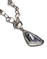 Silver chain necklace with a teardrop-shaped pendant on a white background