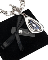 Silver necklace with a blue pendant on a black box, featuring the Wathersetis brand.