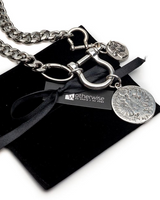 Silver-tone chain necklace with a horsebit clasp, round medallion charms, and a black ribbon with a Motherwise brand tag, displayed on a black velvet pouch against a white background.