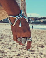 Edgy silver metal cuff bracelet with sculptural design, worn on a wrist, paired with various silver rings.