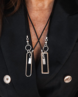 Person wearing a black blazer with a necklace featuring rectangular pendants.