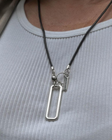 Silver necklace with a rectangular pendant on a person wearing a light gray top.