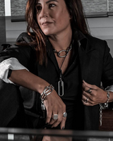 Woman in a black blazer with jewelry sitting in an office setting