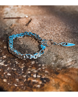 Blue and silver chain bracelet with a pendant on a textured surface