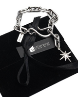 Silver chain bracelet with star charm on a black velvet cushion with 'Otherwise' brand tag.