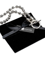 Sterling silver plated ball chain necklace and bracelet set with chunky beads and an organic ring clasp, placed on a suede pouch.