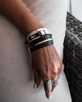 Hand wearing multiple bracelets with a neutral background