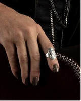 Sterling silver-plated ring with intricate floral engraving, worn on the index finger, paired with a brown leather handbag.