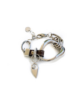 Chunky silver-plated metal cuff bracelet with brown leather and organic shapes, featuring a decorative charm.