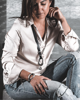 Edgy black leather and silver metal cuff bracelet worn on the wrist, paired with a casual outfit and distressed jeans.
