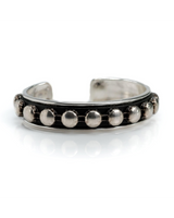 Silver bracelet with circular studs on a white background