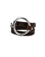 Wrap bracelet made of supple brown leather with a chunky silver-plated hammered metal circle clasp.