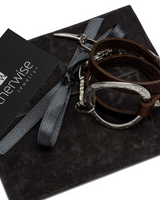 Edgy brown and black wrap leather bracelet featuring silver-plated metal accents on a dark suede pouch.