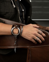Edgy wrap leather and metal bracelet in brown and black, featuring sculpted silver-plated accents, styled with rings.