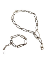 Silver necklace and bracelet set featuring elongated organic links with a unique chain design and carabiner closure.
