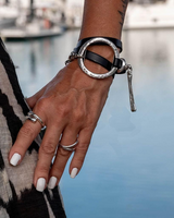 Bold wrap leather and metal statement cuff bracelet featuring multi-strand black leather and a sculpted silver-plated metal ring.