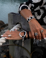 Bold wrap leather and metal statement cuff bracelet features multi-strand black leather and silver-plated sculpted metal.