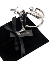 Silver handcuffs with a key on a black velvet box with a bow, branded 'Otherwise'.