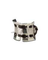 A silver-toned metal cuff bracelet with dark brown leather straps and a small metal spike detail, shown on a plain white background.