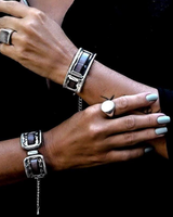 Close-up of hands wearing silver bracelets and rings on a black background