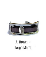 Cuff bracelet with brown band and large metal clasp on a white background