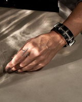 Adjustable silver-plated ring with an irregular bar design, worn on a hand next to a chunky black bracelet.
