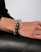 Hand with bracelet and ring on a black leather surface