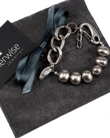 Silver chain and pearl bracelet on a gray surface with 'otherwise jewelry' card.