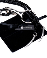 Edgy black and silver chain necklace featuring sculptural tooth pendants, displayed with a black suede pouch.