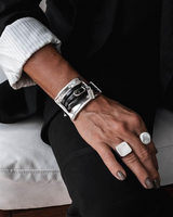 Large metal and leather statement cuff bracelet on a model's wrist, featuring a chunky metallic design and dark leather accents.