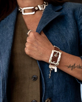 Bold belt buckle necklace and bracelet set showcasing rugged brown leather and chunky silver-plated metal hardware worn on a model.