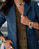 Bold belt buckle necklace and bracelet set featuring brown leather and silver-plated metal hardware, worn with a denim blazer.
