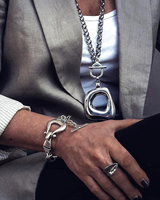 Person wearing silver jewelry including a necklace, bracelet, and ring.