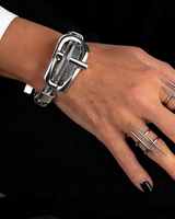 Hand wearing a silver bracelet and multiple rings on a black background