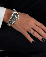 Hand wearing a silver bracelet and ring on a black background