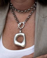 Silver necklace with a unique pendant worn by a person