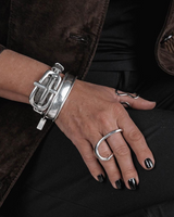 Close-up of a hand wearing a silver bracelet and ring on a dark background