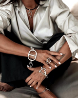 Silver heart necklace set featuring a black leather necklace and two chunky adjustable bracelets worn casually on a model.