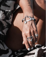 Black leather heart necklace with silver heart charm and two adjustable silver-tone bracelets showcased on a model's wrist.