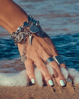 Hand with silver jewelry on a beach