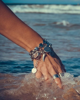Hand with multiple bracelets touching water at the beach